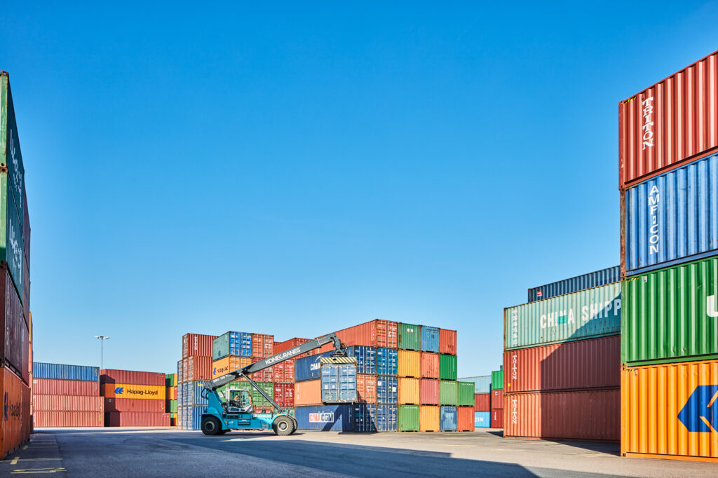 Truck kör med container i containerdepå.