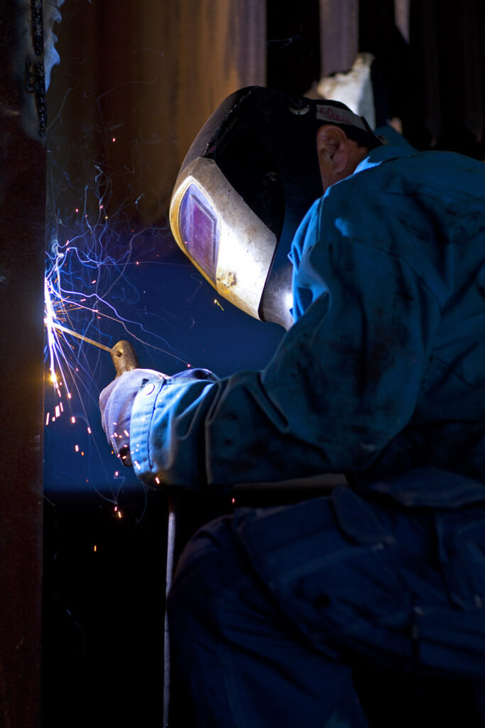 Personal från tekniska avdelningen svetsar, gnistor slår ut och personen har skyddsvisir