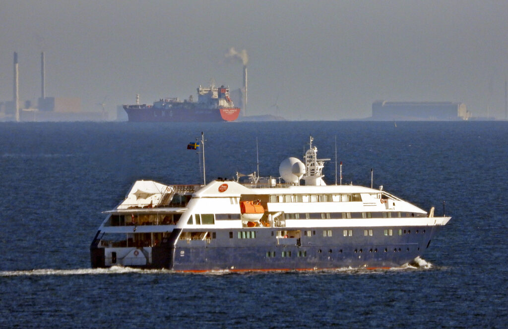kryssare seglar i solnedgången lastfartyg syns på havet bakom